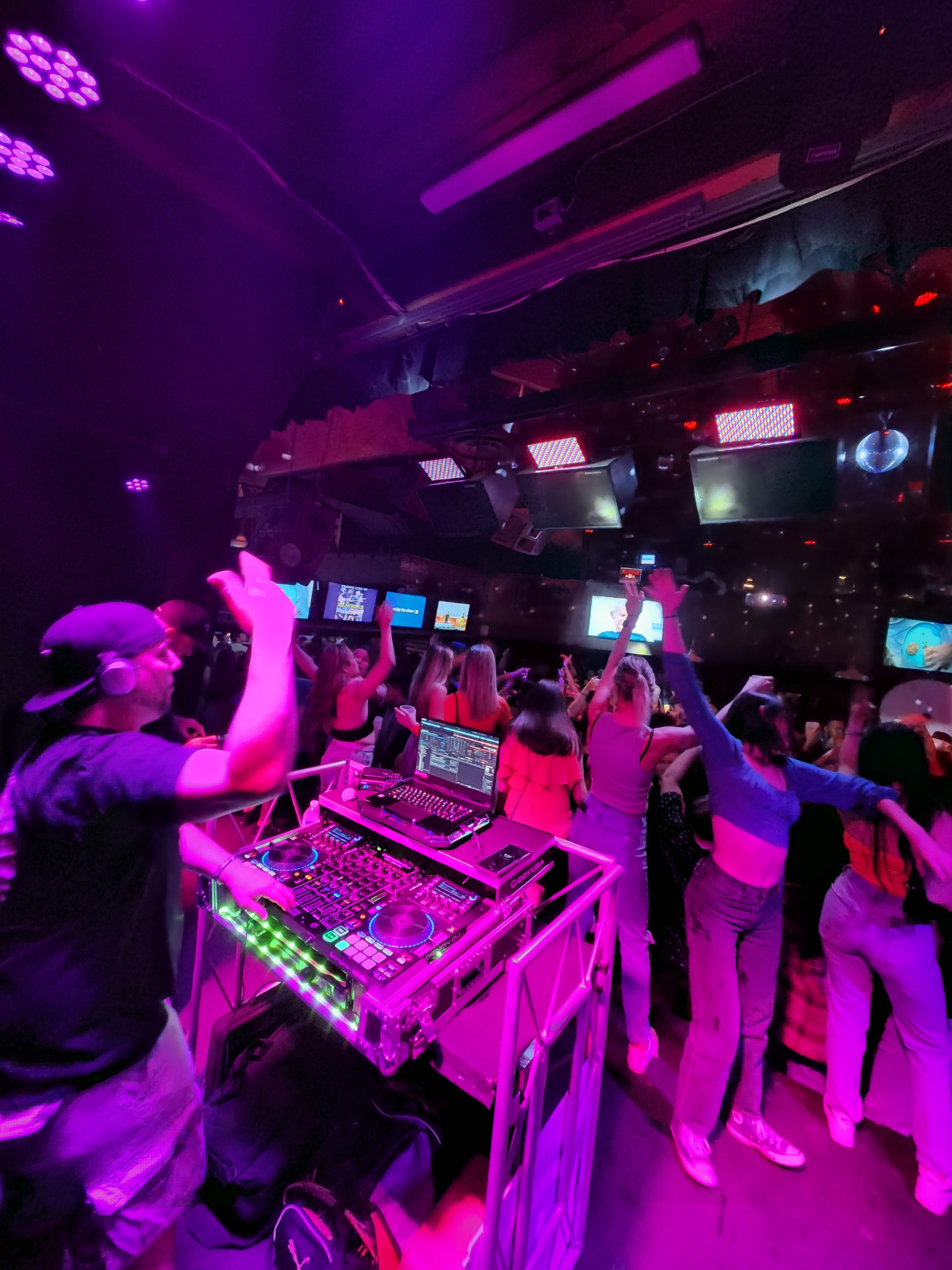 Barry DJing at the decks, pink-lit crowd in front of him