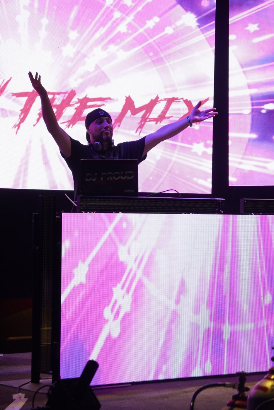 Barry with arms raised at the Bar A booth against a pink LED tunnel