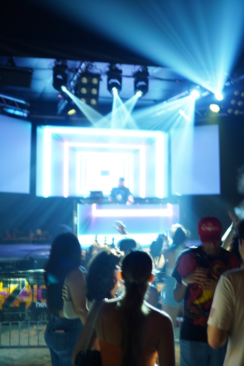 Blue light beams over the crowd at Bar A, stage in the distance
