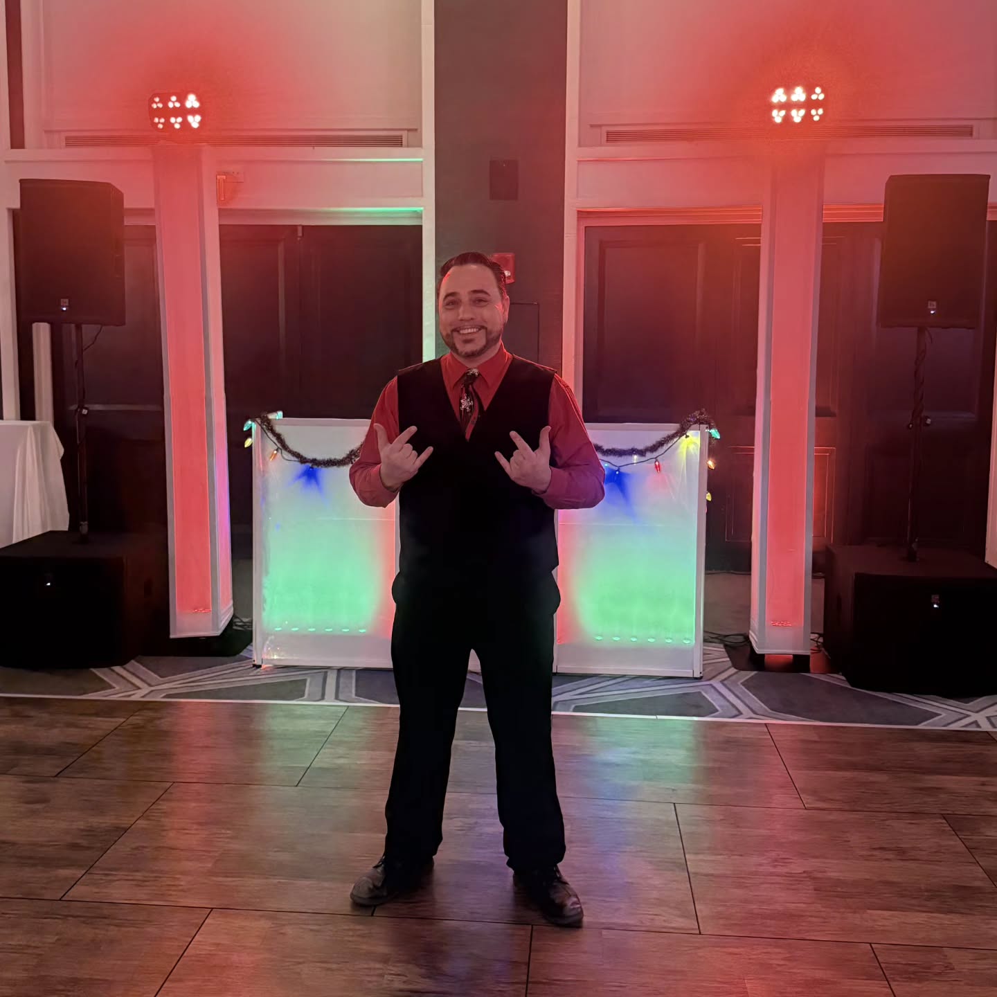 Barry in vest and tie at his white facade setup — Hilton holiday corporate party