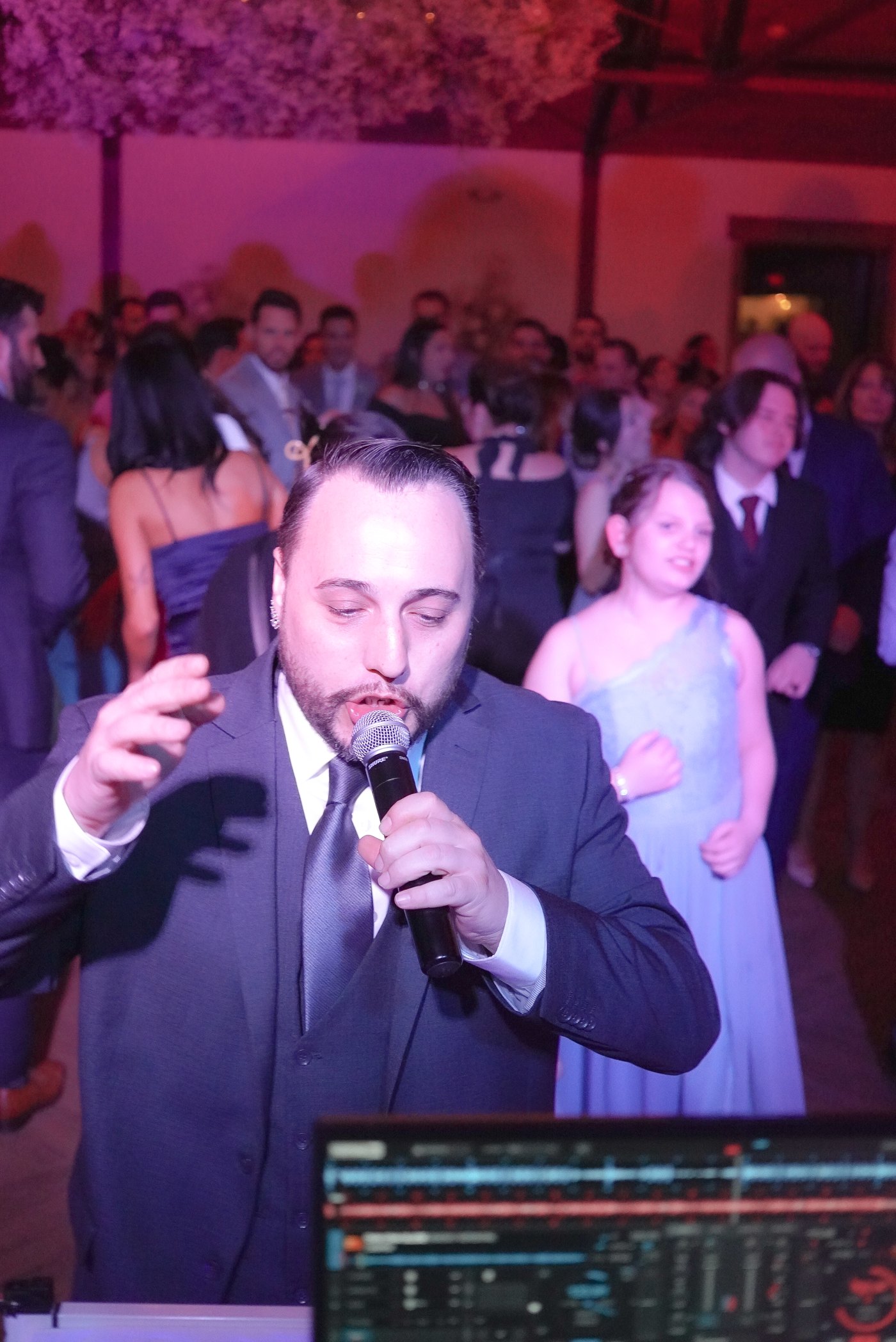 Barry in a suit hyping the crowd on the microphone at a wedding reception