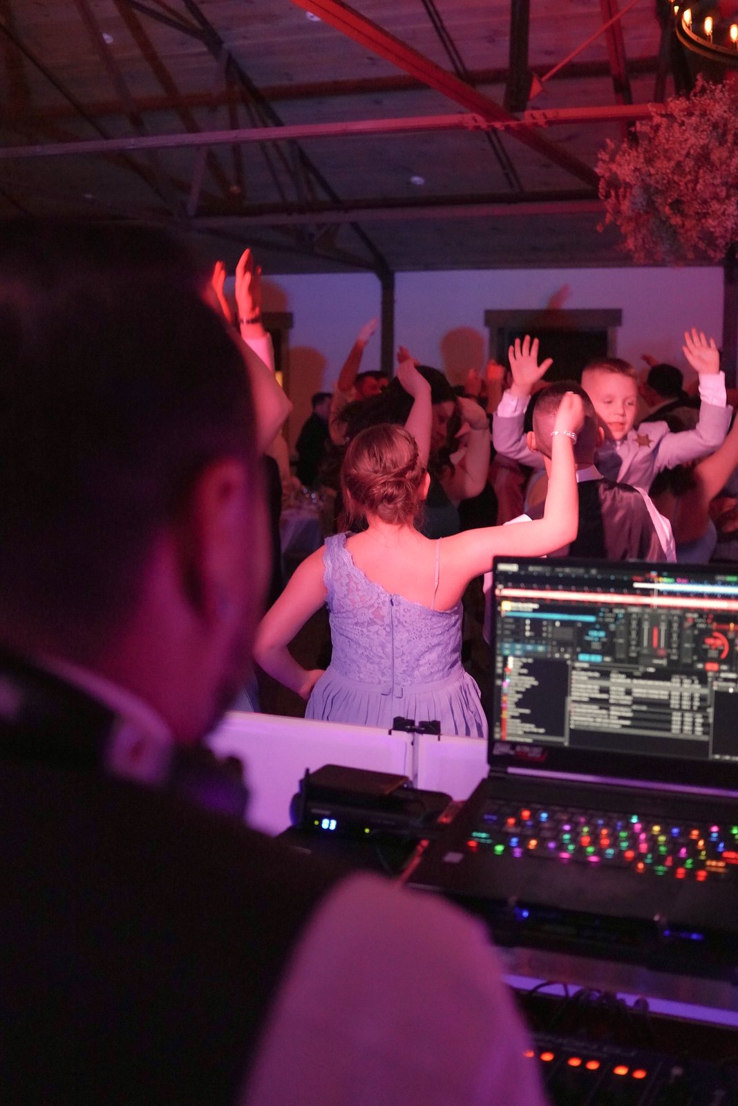 Over Barry's shoulder: wedding guests with hands up on a packed dance floor