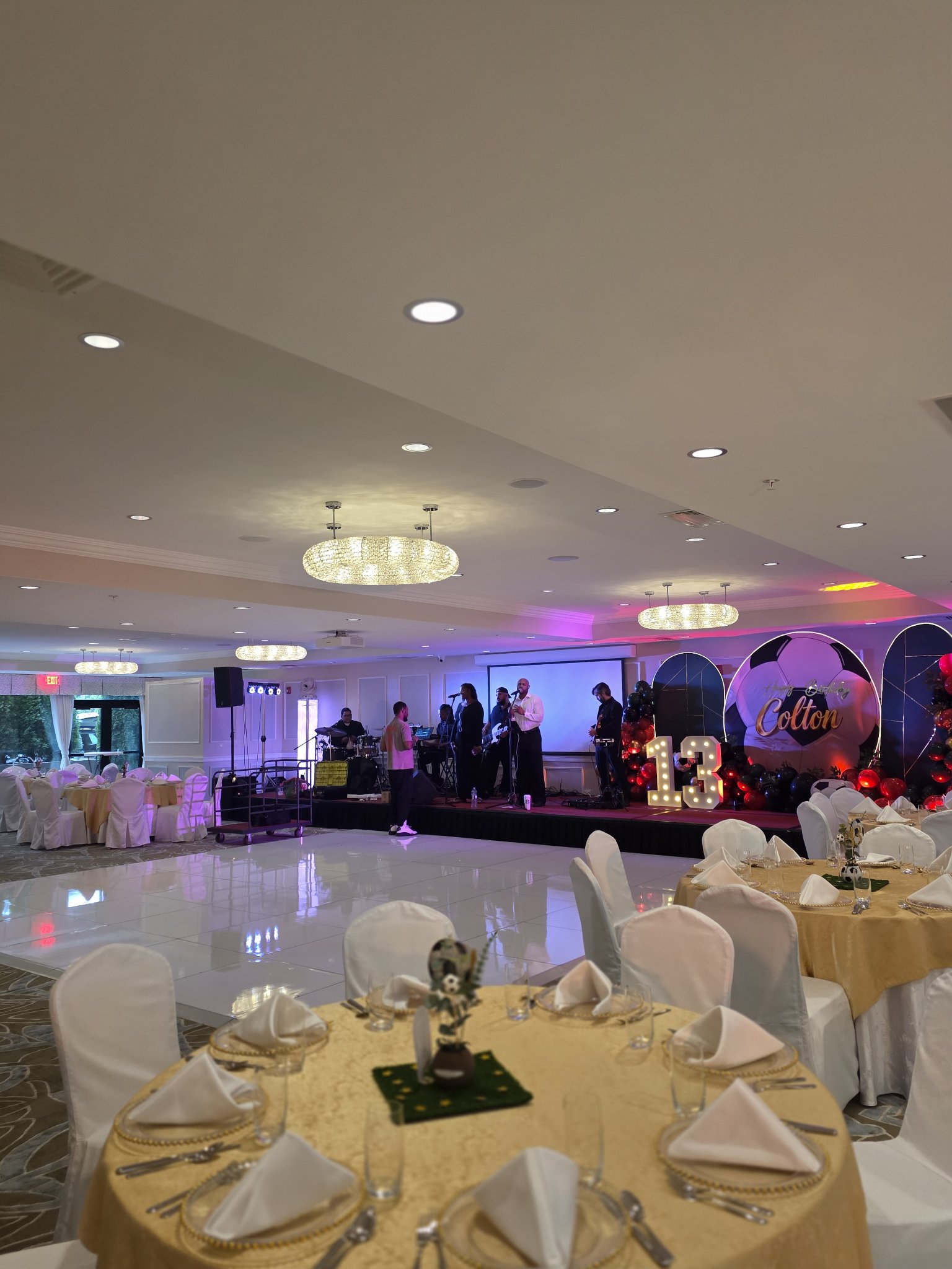 Ballroom set for a 13th birthday — stage with live band, dance floor and dressed tables