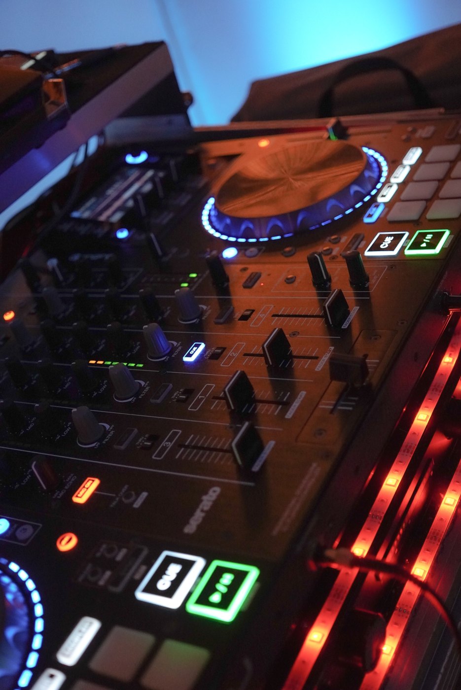 Close-up of the DJ controller glowing with colored pads and jog wheel