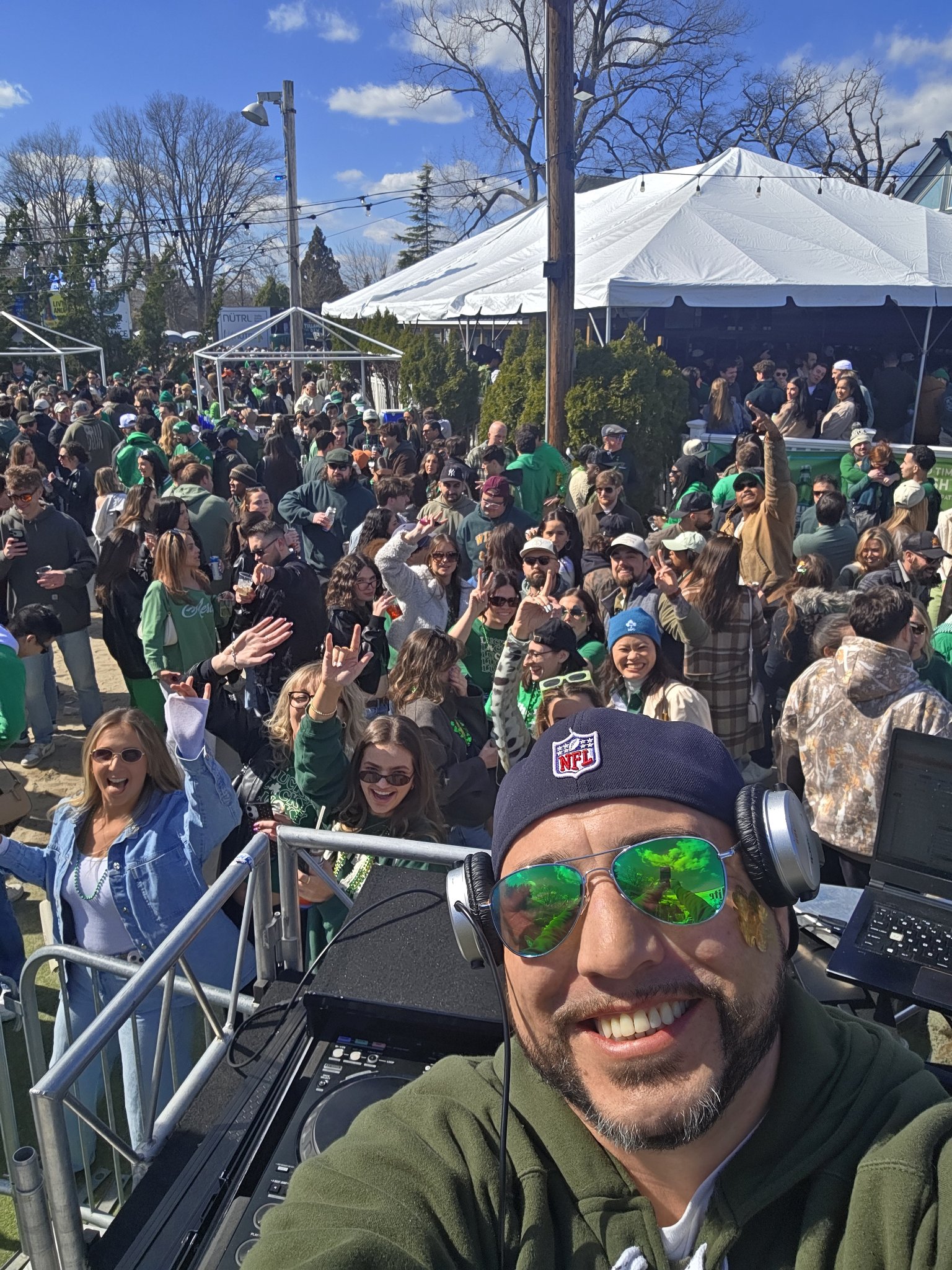 Barry selfie from the DJ booth at a packed outdoor day party — huge crowd dancing under tents
