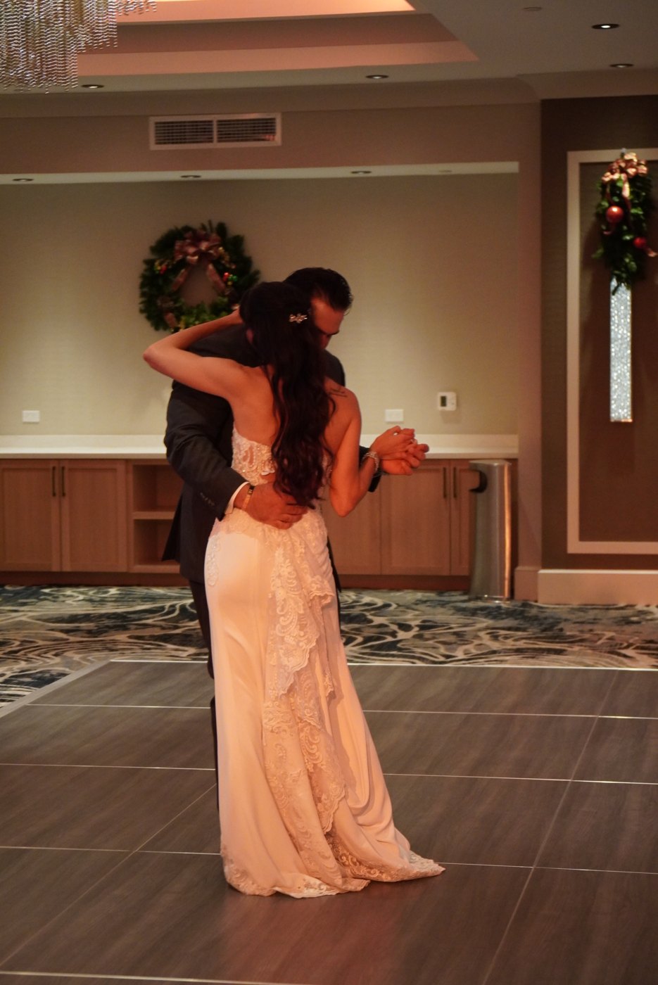 Groom dipping the bride during their first dance in a warm lobby