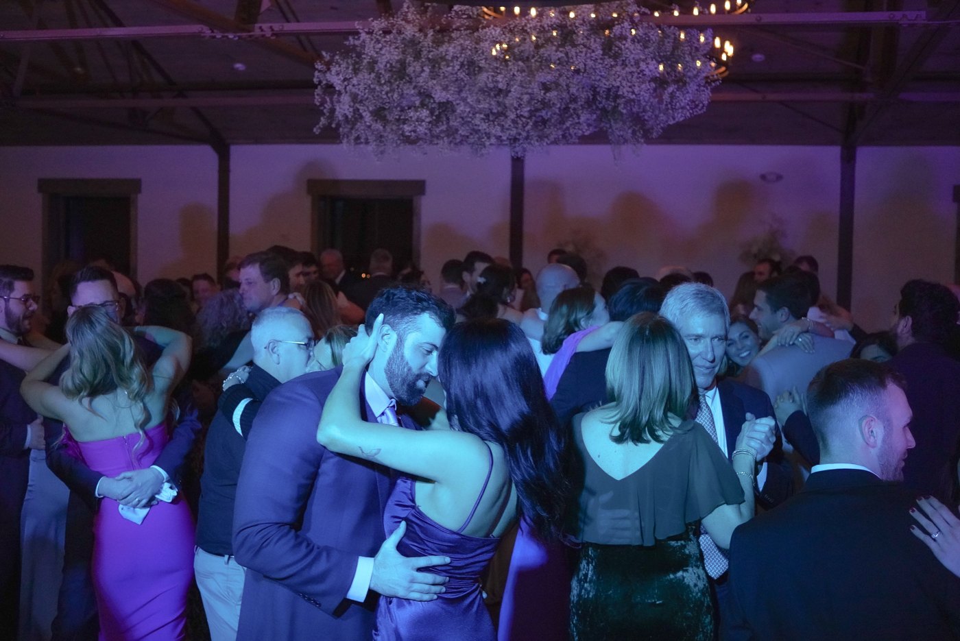 Packed wedding dance floor — couples dancing under the chandeliers