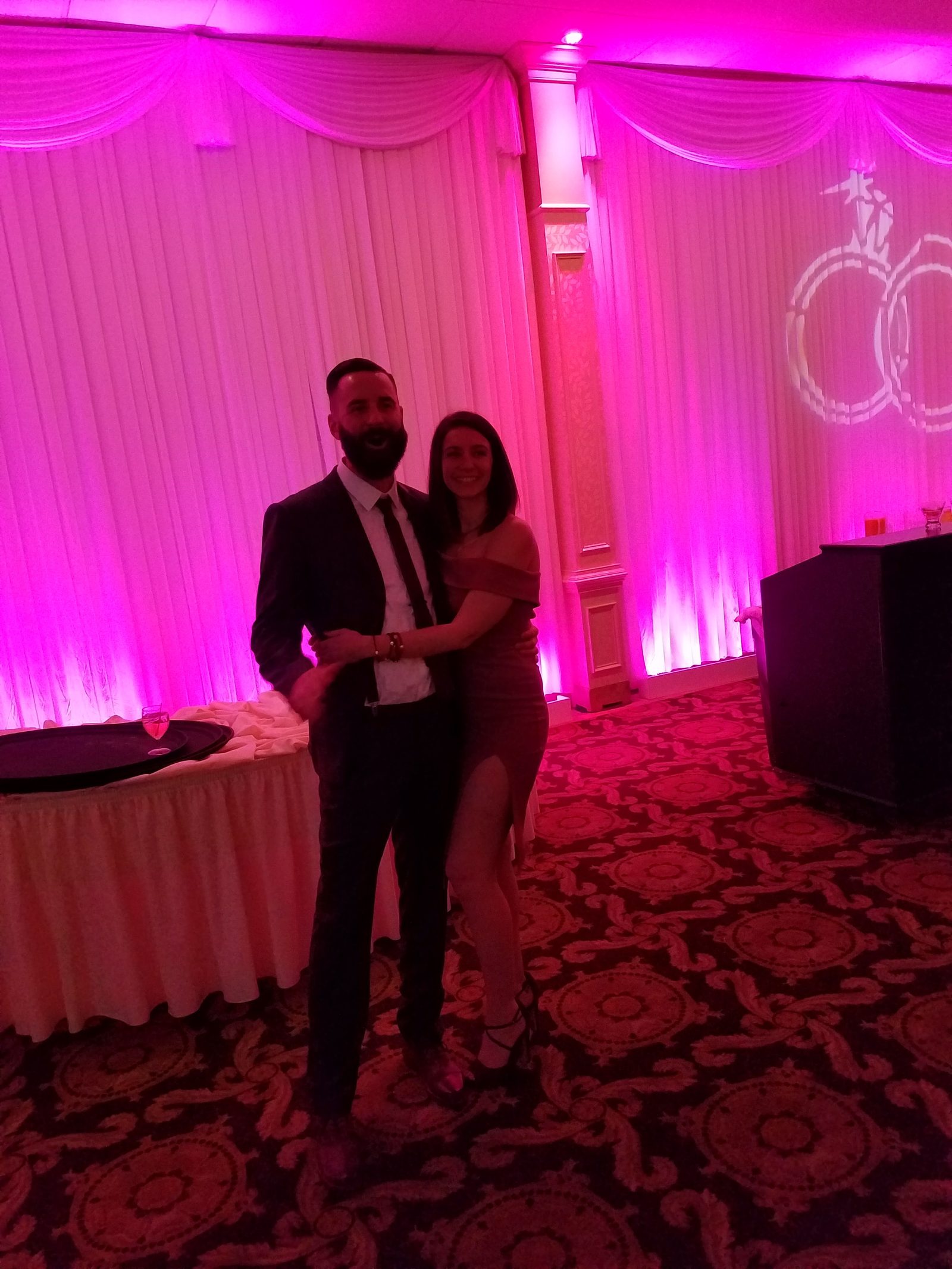 Newlywed couple on the dance floor under a projected monogram light display