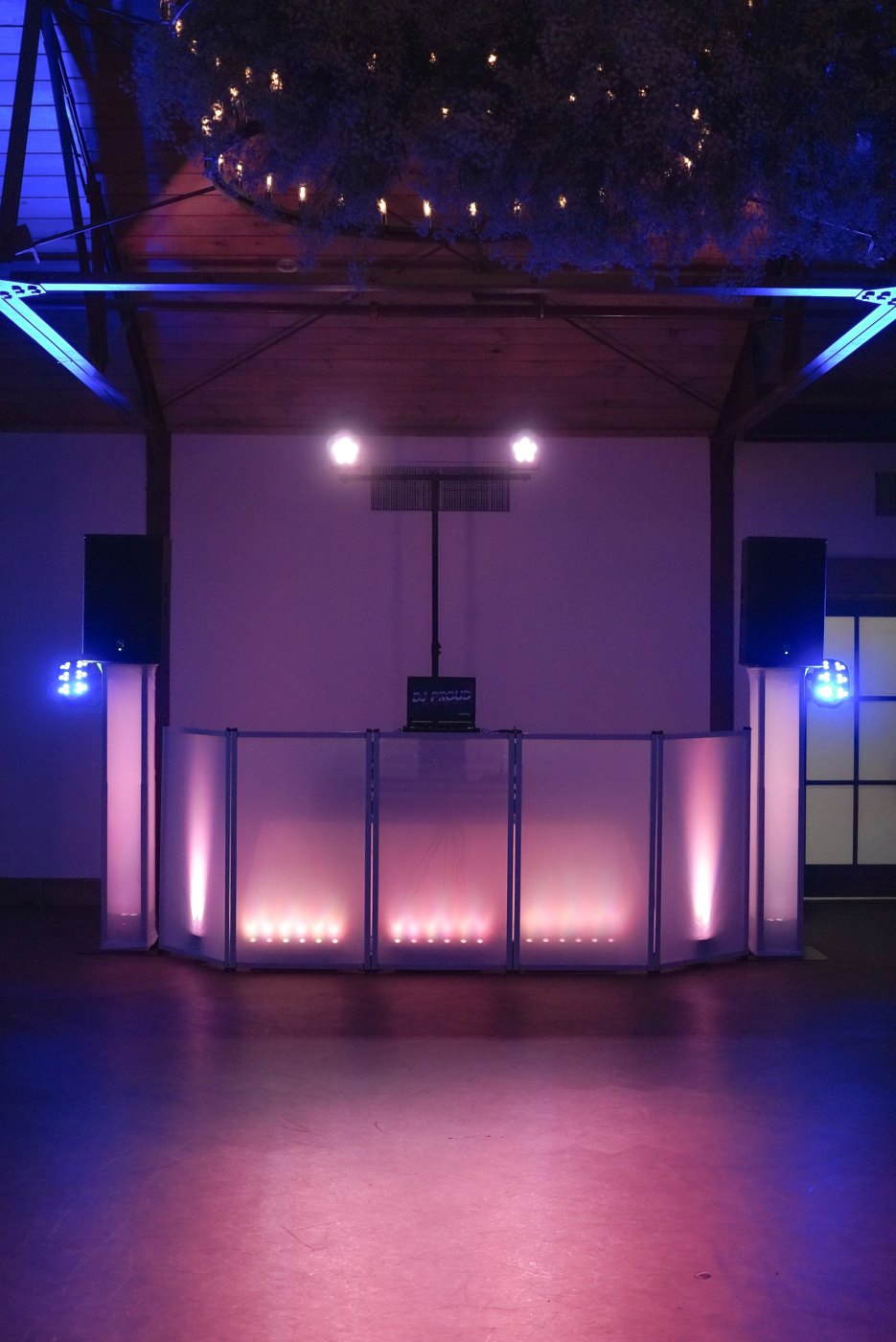 The white DJ facade glowing pink in an empty ballroom with uplighting