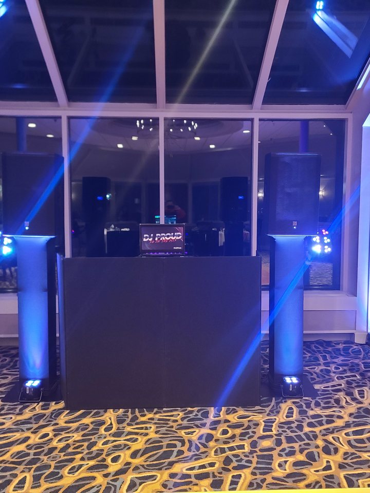 The Proud black DJ setup with blue up-lit truss towers in a glass conservatory at night