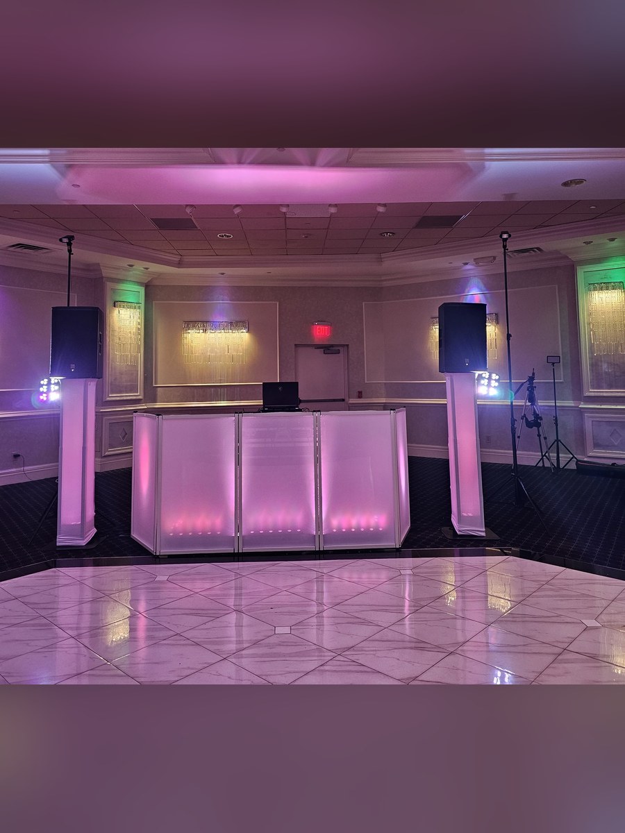 The Prouder white DJ setup glowing rose-gold between two up-lit towers on a marble dance floor