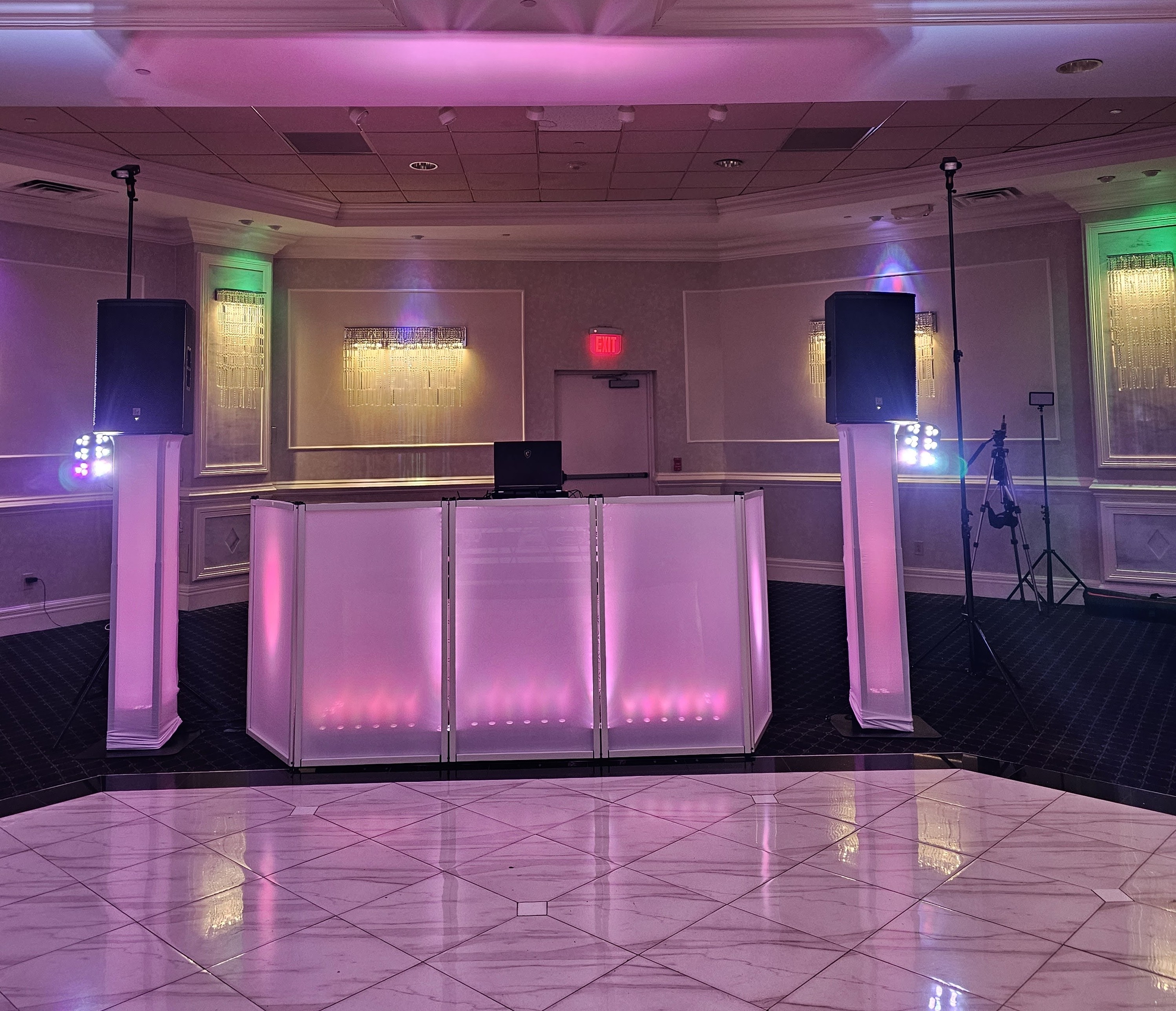 The Prouder white DJ setup glowing rose-gold between two up-lit towers on a marble dance floor
