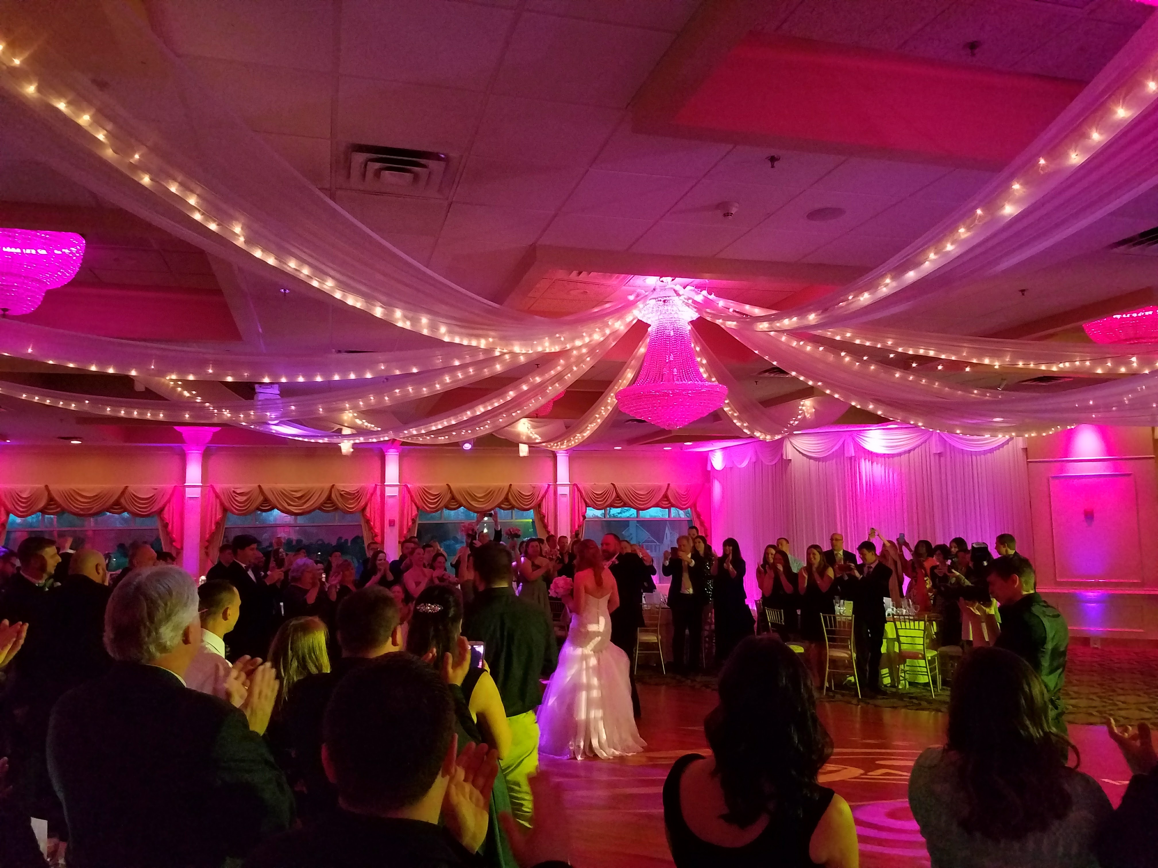 Packed wedding reception ballroom with draped ceiling