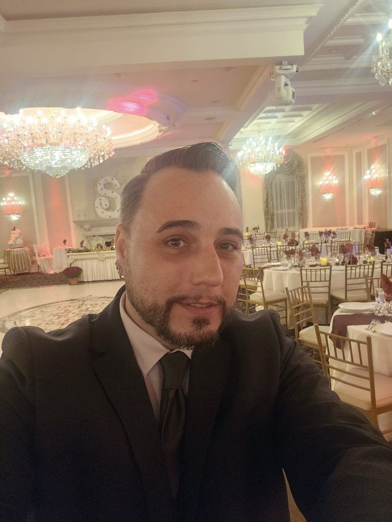 Barry in a black suit and tie at an elegant chandelier-lit wedding reception