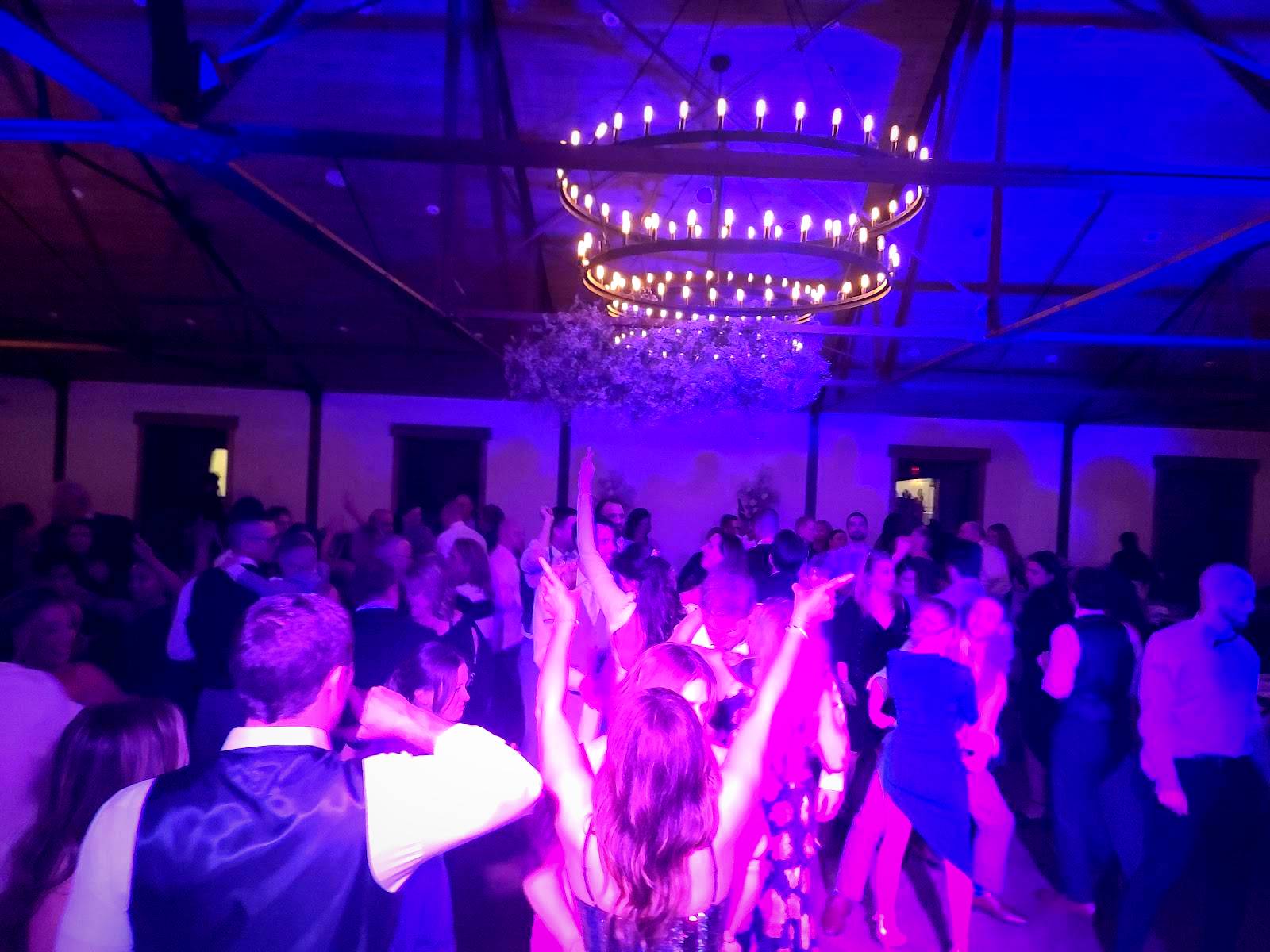 Packed dance floor under a chandelier and purple event lighting